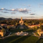 "Stunning aerial view of Stanford University Main Quad at sunset with Memorial Church, sandstone buildings, and palm trees on the historic campus in California"